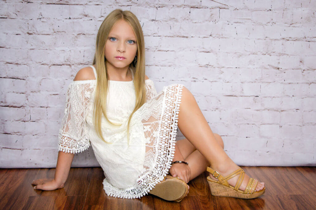 blonde girl in lace dress sitting modeling